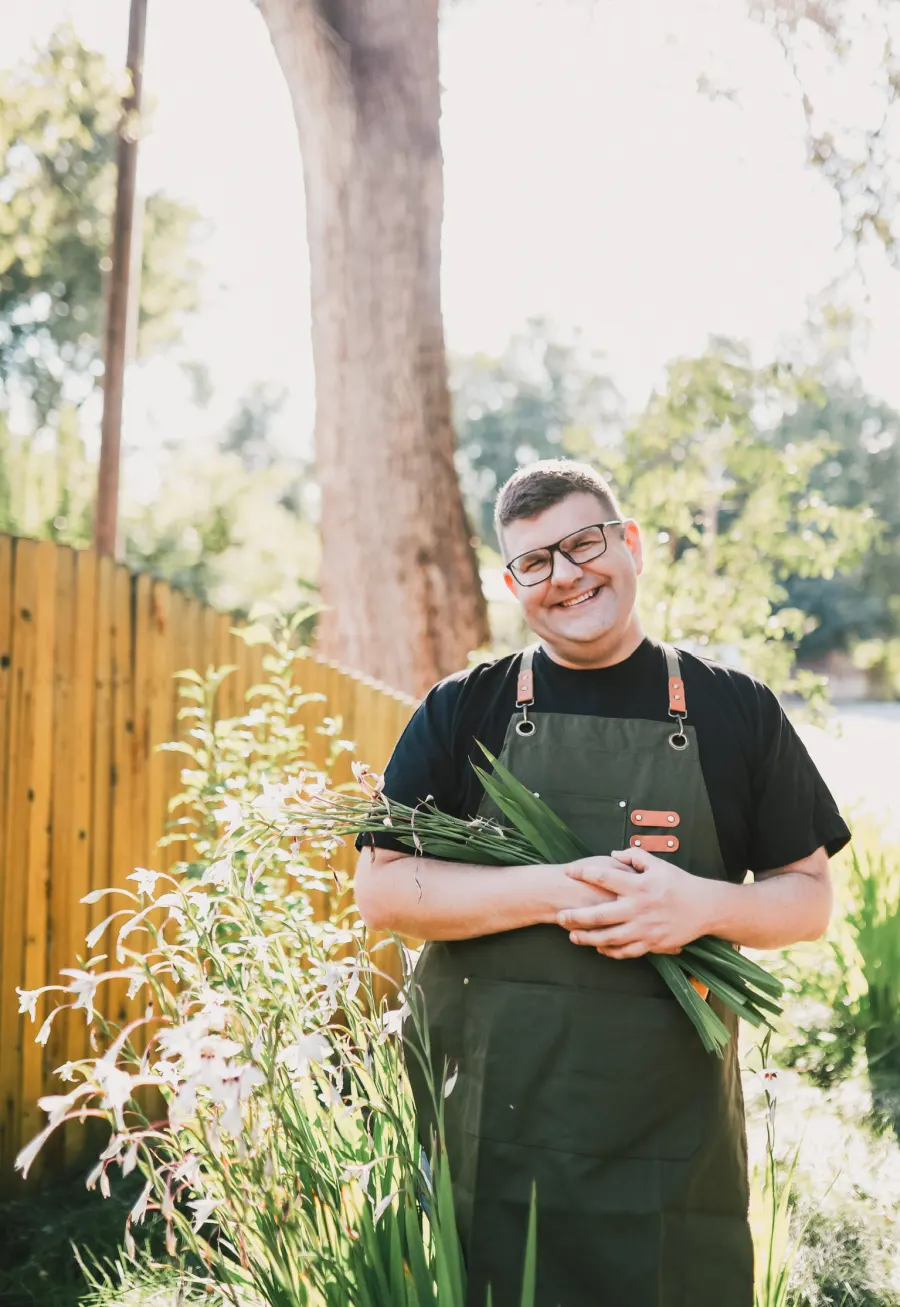 Alex Abel, founder of Garden Lady Concepts, smiling in a sunny garden with fresh-cut flowers
